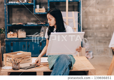 Female artist wears black hat posing near picture indoor the studio 139698851