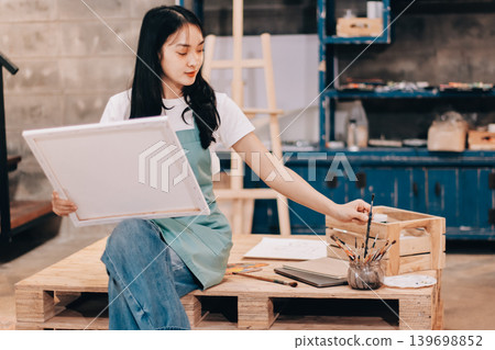 Female artist wears black hat posing near picture indoor the studio 139698852