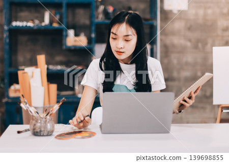 Female artist wears black hat posing near picture indoor the studio Female artist wears black hat posing near picture indoor the studio 139698855