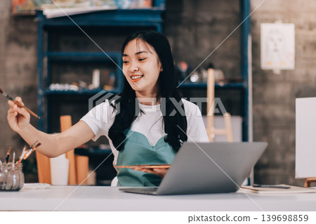 Female artist wears black hat posing near picture indoor the studio Female artist wears black hat posing near picture indoor the studio 139698859