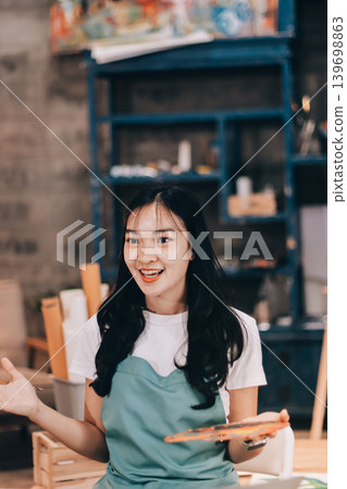 Female artist wears black hat posing near picture indoor the studio 139698863