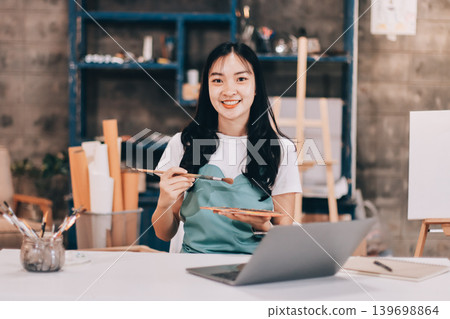 Female artist wears black hat posing near picture indoor the studio 139698864