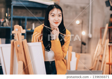 Female artist wears black hat posing near picture indoor the studio Female artist wears black hat posing near picture indoor the studio 139698871