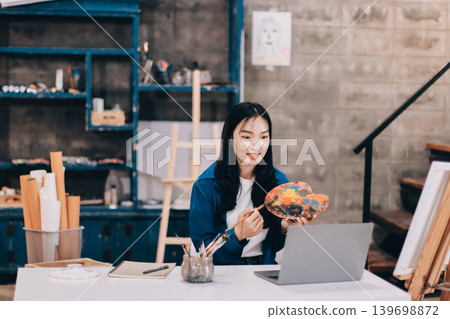 Female artist wears black hat posing near picture indoor the studio 139698872