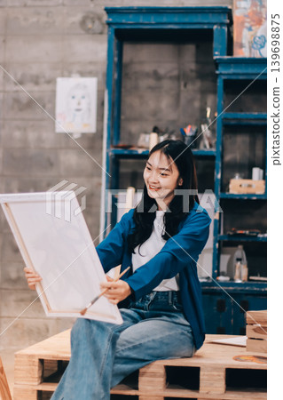 Female artist wears black hat posing near picture indoor the studio 139698875