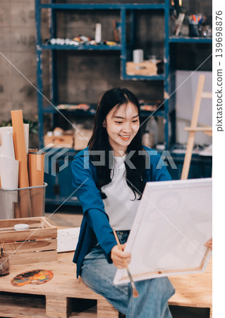 Female artist wears black hat posing near picture indoor the studio Female artist wears black hat posing near picture indoor the studio 139698876