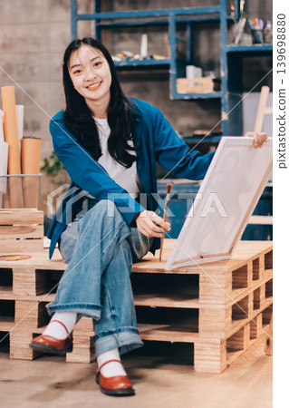 Female artist wears black hat posing near picture indoor the studio 139698880