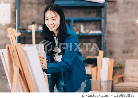 Female artist wears black hat posing near picture indoor the studio Female artist wears black hat posing near picture indoor the studio 139698882