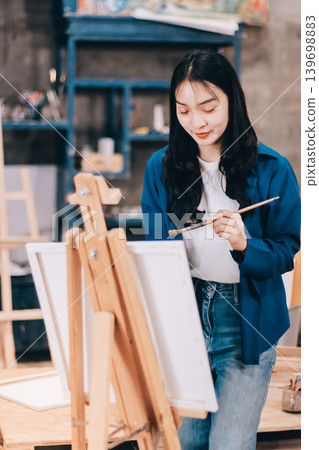 Female artist wears black hat posing near picture indoor the studio 139698883