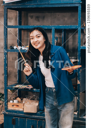 Female artist wears black hat posing near picture indoor the studio 139698889