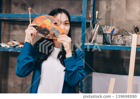 Female artist wears black hat posing near picture indoor the studio Female artist wears black hat posing near picture indoor the studio 139698890