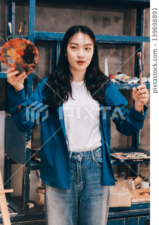 Female artist wears black hat posing near picture indoor the studio 139698891