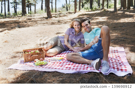 Happy couple, portrait and relax in nature for picnic, love or support in affection, date or outdoor bonding. Woman and man on floor with basket of fruit for eating or romantic dinner in forest Happy couple, portrait and relax in nature for picnic, love or support in affection, date or outdoor bonding. Woman and man on floor with basket of fruit for eating or romantic dinner in forest 139698912