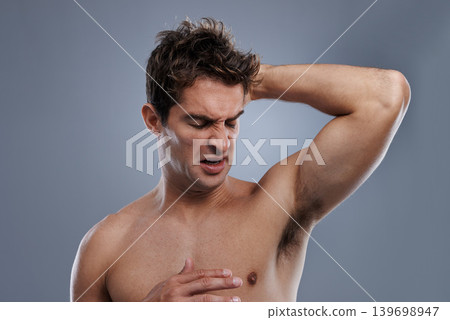 Armpit, stink and man with body odor, poor hygiene and routine on grey studio background for deodorant, cleaning and skincare. Underarm, bad smell and model with hyperhidrosis, sweating or cosmetics 139698947