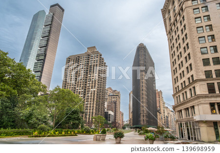 New york, usa august 18,2024. Flatiron building, featuring a classic architectural landmark, rising among modern skyscrapers in a manhattan urban park background New york, usa august 18,2024. Flatiron building, featuring a classic architectural landmark, rising among modern skyscrapers in a manhattan urban park background 139698959