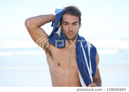Travel, beach and portrait of man with towel for swimming in ocean on vacation, holiday or adventure. Serious, handsome and young person by sea with confidence for summer weekend trip in Australia. Travel, beach and portrait of man with towel for swimming in ocean on vacation, holiday or adventure. Serious, handsome and young person by sea with confidence for summer weekend trip in Australia. 139698969