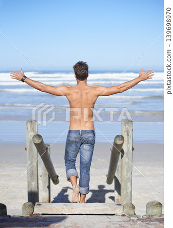 Walking, arms up and back of man at the beach on tropical vacation, adventure or holiday. Travel, stairs and confident shirtless male person on outdoor steps by ocean or sea for summer weekend trip. Walking, arms up and back of man at the beach on tropical vacation, adventure or holiday. Travel, stairs and confident shirtless male person on outdoor steps by ocean or sea for summer weekend trip. 139698970