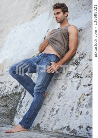 Fashion, outdoor and man by rock in sexy pose in trendy clothes, casual style and outfit in nature. Masculine, serious model and attractive person by wall with confidence, pride or stylish on weekend 139699021