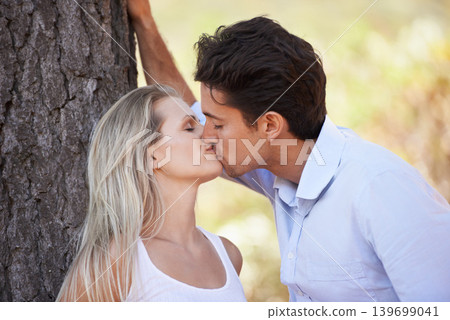 Couple, kiss and love by tree for affection, care or romance in nature, outdoor park or forest. Young man and woman kissing for embrace, relationship or bonding intimacy in woods for date or freedom Couple, kiss and love by tree for affection, care or romance in nature, outdoor park or forest. Young man and woman kissing for embrace, relationship or bonding intimacy in woods for date or freedom 139699041