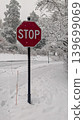 Red stop sign on snow-covered roadside during winter blizzard. 139699069