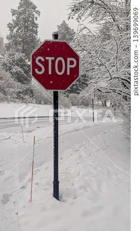 Red stop sign on snow-covered roadside during winter blizzard. Red stop sign on snow-covered roadside during winter blizzard. 139699069
