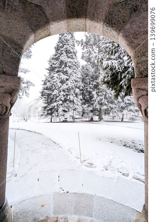 Snowy winter landscape framed by stone archway of a building. Snowy winter landscape framed by stone archway of a building. 139699076