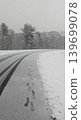 Human footprints and tire tracks on wet asphalt road during winter snowfall. 139699078