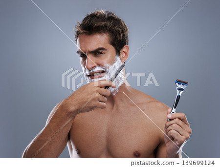 Man, choice and razor in studio, shaving cream or portrait for grooming by grey background. Person, model and decision for blade with beard, facial hair removal and doubt product for cosmetic change Man, choice and razor in studio, shaving cream or portrait for grooming by grey background. Person, model and decision for blade with beard, facial hair removal and doubt product for cosmetic change 139699124