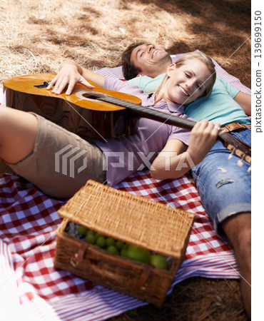 Happy couple, picnic and playing guitar for love, romance or music in outdoor bonding, fun or relaxing together in nature. Man and woman smile with instrument for acoustic sound or songs outside Happy couple, picnic and playing guitar for love, romance or music in outdoor bonding, fun or relaxing together in nature. Man and woman smile with instrument for acoustic sound or songs outside 139699150