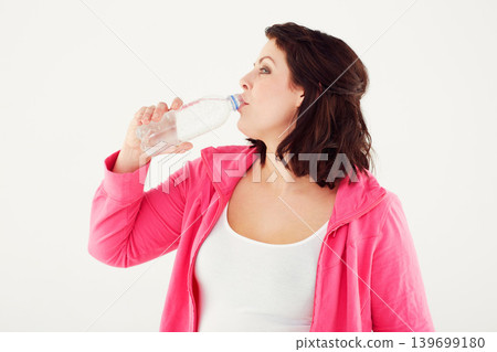 Woman, fitness and drinking water for hydration after workout or exercise on a white studio background. Female person or plus size and mineral drink in natural wellness on break or mockup space Woman, fitness and drinking water for hydration after workout or exercise on a white studio background. Female person or plus size and mineral drink in natural wellness on break or mockup space 139699180