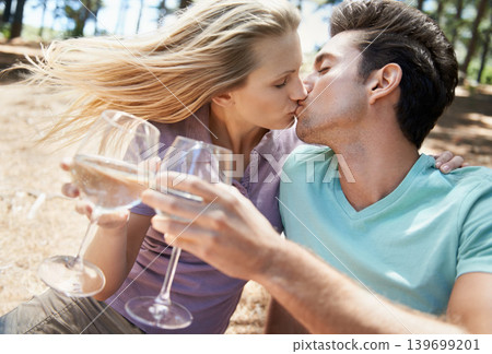 Couple, kiss and wine in nature or forest for celebration of love, holiday and valentines day. Man and woman together with glasses, alcohol drinks and toast on outdoor date for anniversary in woods Couple, kiss and wine in nature or forest for celebration of love, holiday and valentines day. Man and woman together with glasses, alcohol drinks and toast on outdoor date for anniversary in woods 139699201