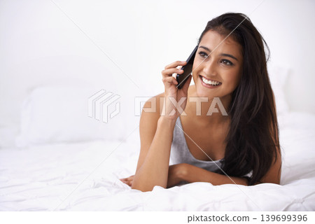 Happy woman, phone call and conversation on bed for communication or networking at home. Face of young female person smile and talking on mobile smartphone in relax or lying in bedroom for discussion Happy woman, phone call and conversation on bed for communication or networking at home. Face of young female person smile and talking on mobile smartphone in relax or lying in bedroom for discussion 139699396