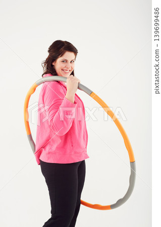 Happy woman, portrait and hoop for fitness, exercise or workout in balance on a white studio background. Active female person smile with plastic circle for training, practice or health and wellness Happy woman, portrait and hoop for fitness, exercise or workout in balance on a white studio background. Active female person smile with plastic circle for training, practice or health and wellness 139699486