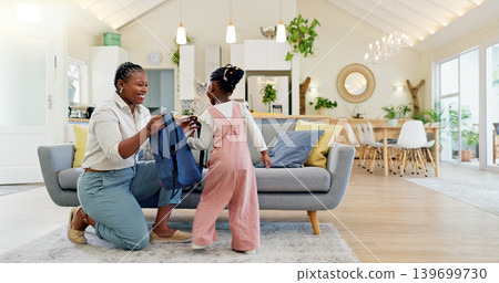 Talking, happy and a mother with a child getting ready for school in the morning. Kiss, laughing and an African mom helping a little girl with a bag in the living room of a house for kindergarten Talking, happy and a mother with a child getting ready for school in the morning. Kiss, laughing and an African mom helping a little girl with a bag in the living room of a house for kindergarten 139699730