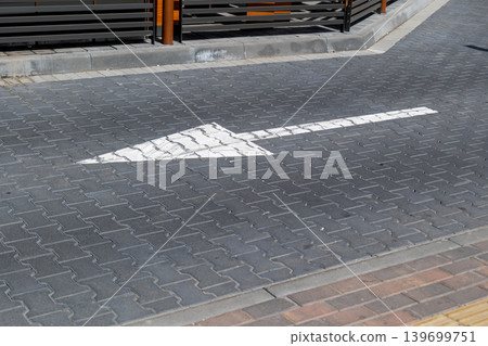 Road marking pointing forward on a gray pavement in a city near a parking area with nearby structures and barriers Road marking pointing forward on a gray pavement in a city near a parking area with nearby structures and barriers 139699751