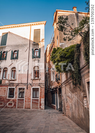 Atmospheric empty Venetian street with historic Italian architecture at daylight Atmospheric empty Venetian street with historic Italian architecture at daylight 139700162