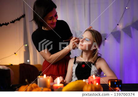 Mom Doing Spooky Halloween Makeup For Daughter During Family Celebration At Home Mom Doing Spooky Halloween Makeup For Daughter During Family Celebration At Home 139700374