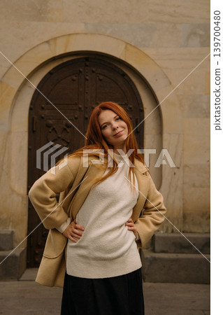 red-haired girl poses confidently in front of an old door in a city during daytime red-haired girl poses confidently in front of an old door in a city during daytime 139700480