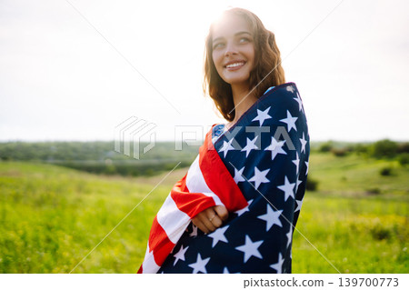 Young woman with american USA flag on blooming meadow. Independence Day, 4th July. Young woman with american USA flag on blooming meadow. Independence Day, 4th July. 139700773