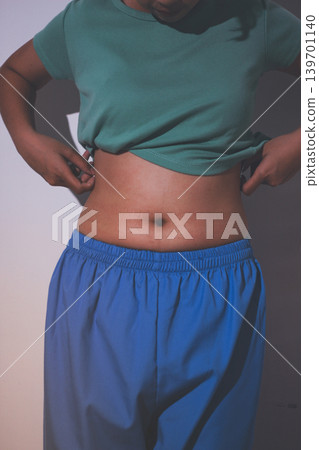 Overweight woman body with hands touching belly fat Overweight woman body with hands touching belly fat 139701140