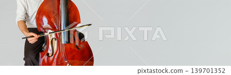 Contrabass player trying to play stringless double bass with copy space Contrabass player trying to play stringless double bass with copy space 139701352