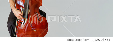 Person holding a stringless contrabass and bow during damage inspection, with copy space on the right. 139701354