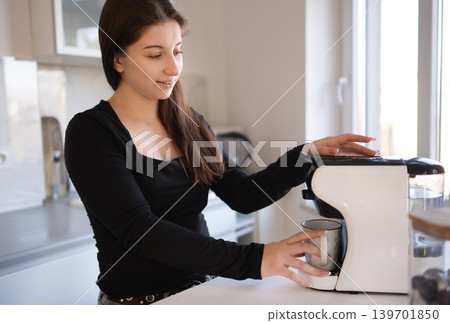 Girl preparing a cup of coffee with coffee machine before starting her day at home 139701850