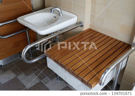 A wooden diaper changing table installed in a public restroom. A wooden diaper changing table installed in a public restroom. 139701871