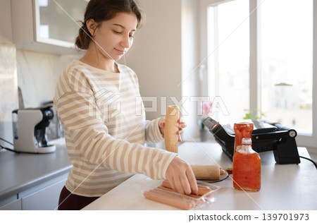 Girl stands at kitchen counter, Preparing Hot Dog In Kitchen 139701973