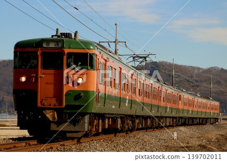 一列塗裝湘南塗裝的日本國鐵115系列車駛過彎道。 139702011