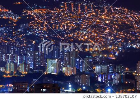 Night view of Medellín, Colombia: A carpet of lights spread across the mountain slopes and the city's nightscape. 139702107