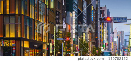 Tokyo, Japan - Oct 14 2024, panoramic view of main street of Ginza district, tall glass facades of skyscrapers along which people walk, cars drive along road, in evening with illumination, Tokyo Japan Tokyo, Japan - Oct 14 2024, panoramic view of main street of Ginza district, tall glass facades of skyscrapers along which people walk, cars drive along road, in evening with illumination, Tokyo Japan 139702152