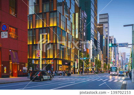 Tokyo, Japan - Oct 14 2024, panoramic view of main street of Ginza district, tall glass facades of skyscrapers along which people walk, cars drive along road, in evening with illumination, Tokyo Japan Tokyo, Japan - Oct 14 2024, panoramic view of main street of Ginza district, tall glass facades of skyscrapers along which people walk, cars drive along road, in evening with illumination, Tokyo Japan 139702153