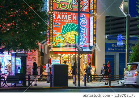 Tokyo, Japan - Oct 14 2024, panoramic view of a street in Akihabara district with female promoters in short dresses against backdrop of shop and restaurant windows, illuminated at night, Tokyo, Japan Tokyo, Japan - Oct 14 2024, panoramic view of a street in Akihabara district with female promoters in short dresses against backdrop of shop and restaurant windows, illuminated at night, Tokyo, Japan 139702173